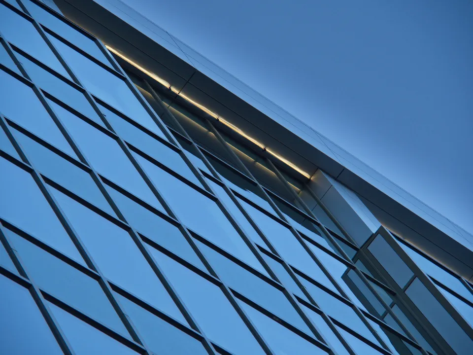 Diagonal lines of a glass building facade against a blue sky